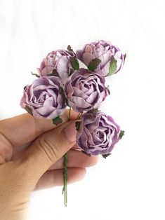 a person holding purple flowers in their hand