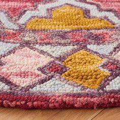 a colorful rug is on the floor with wood floors in the background and an orange, yellow, pink, and purple area rug