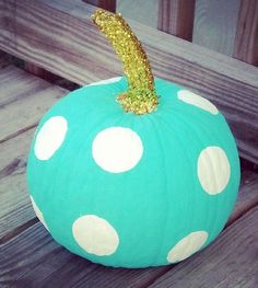 a blue and white polka dot pumpkin sitting on top of a wooden bench