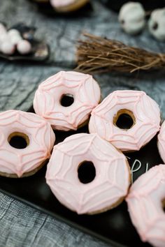 pink donuts sitting on top of a black plate next to other doughnuts