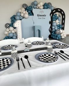 the table is set with black and white checkered plates, silverware, and balloons