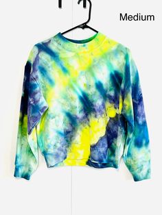 a blue and yellow tie - dyed sweatshirt hanging on a hanger with the word medium written below it