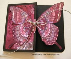 a pink butterfly is on top of a black card with string and bead work