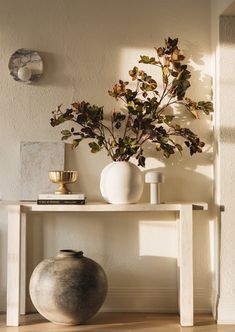 a white table with two vases and a plant sitting on it's side