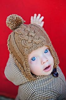 a little boy wearing a knitted hat with a pom - pom on it