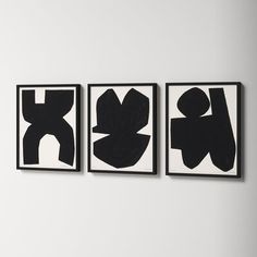 three black and white paintings hanging on the wall