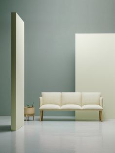 a white couch sitting on top of a hard wood floor next to a gray wall