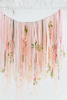 pink and green streamers hanging from the ceiling in front of a white wall with flowers on it