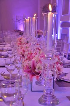 the table is set with candles, flowers and wine glasses for an elegant wedding reception