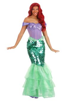 a woman in a green and purple mermaid costume with her hands out to the side