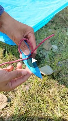 someone is tying a string to an origami kite in the grass with their hands