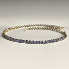 Our Tanzanite Tennis Bracelet, available in 14K or 18K gold, exudes elegance with mesmerizing December birthstone tanzanite, perfect for dainty stacking. This stunning bracelet adds a touch of personal luxury to any look, making it an ideal choice for an anniversary gift or a unique piece of personalized jewelry for her.  𝐅𝐞𝐚𝐭𝐮𝐫𝐞𝐬: * 𝐌𝐚𝐝𝐞 𝐭𝐨 𝐎𝐫𝐝𝐞𝐫 * 𝐌𝐞𝐭𝐚𝐥: 𝟏𝟒𝐊 | 𝟏𝟖𝐊 * 𝐁𝐚𝐧𝐝 𝐂𝐨𝐥𝐨𝐫𝐬: Rose Gold, Yellow Gold & White Gold * 𝐀𝐩𝐩𝐫𝐨𝐱𝐢𝐦𝐚𝐭𝐞 𝐆𝐫𝐨𝐬𝐬 𝐖𝐞 Fine Jewelry Sapphire Bangle Bracelet, Fine Jewelry Sapphire Bracelets, Sapphire Tennis Bracelet With 17 Jewels, 14k Gold Bracelet With 17 Jewels, Yellow Gold Tanzanite Jewelry In Round Cut, Fine Jewelry Bracelets With Round Cut Gemstone, 14k Gold Bangle Bracelet With Prong Setting, 14k Gold Jubilee Bracelet With Round Cut, Round Cut Gemstone Bracelets For Anniversary