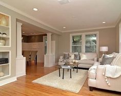 a living room filled with furniture and a fire place in the middle of a wooden floor