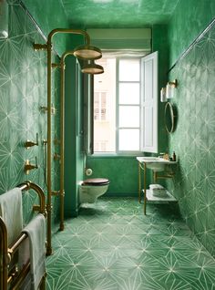 a bathroom with green walls and gold fixtures