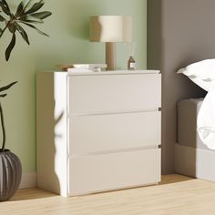 a white dresser sitting next to a lamp on top of a wooden floor near a bed