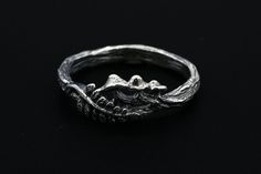 "Step into the whimsical charm of nature with our Mushroom and Fern Ring. Painstakingly handcrafted in sterling silver, this unique design features delightful mushrooms and a fern branch, all resting on a band with a realistic wood texture. This piece exudes the enchanting beauty of an undisturbed forest. This ring is an ideal choice for those who appreciate a piece that combines the playful charm of nature-inspired jewelry with the expertise of artisan craftsmanship. The mushrooms and fern, sym Unique Hand Forged Sterling Silver Jewelry, Nature-inspired Engraved Silver Jewelry, Heirloom Sterling Silver Hand Cast Jewelry, Heirloom Handmade Sterling Silver Jewelry, Heirloom Hand Cast Sterling Silver Jewelry, Heirloom Style Sterling Silver Nickel-free Jewelry, Artisan Engraved Jewelry For Promise Ring, Heirloom Style Nickel-free Sterling Silver Jewelry, Artisan Engraved Promise Ring Jewelry