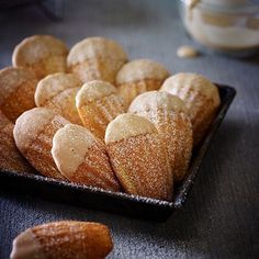 several pastries are arranged on a black tray with powdered sugar in the middle