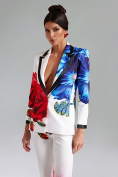 a woman in white pants and a floral jacket with red flowers on the side, posing