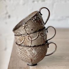 three coffee mugs stacked on top of each other, one with an intricate design