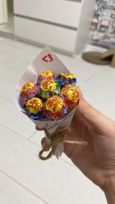 a hand holding a bunch of candy wrapped in twine on top of a white floor