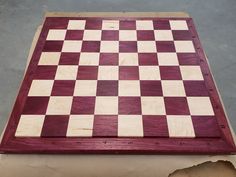 a wooden checker board sitting on top of a piece of wood with holes in it