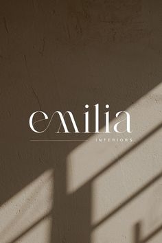 an image of the word emilia written in white on a beige wall with shadows