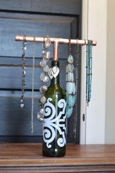 a wine bottle with beads hanging from it's side sitting on a wooden table