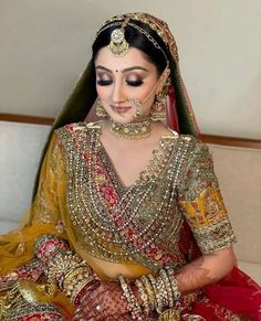 a woman in a red and gold bridal outfit sitting on a couch with her eyes closed