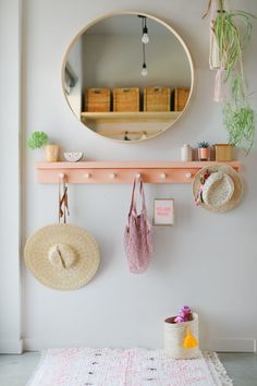 a mirror and some hats hanging on a wall next to a rug with other items