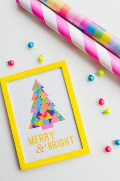 a merry and bright christmas card next to a candy cane on a white surface with colorful candies