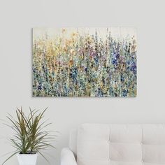 an abstract painting hangs on the wall above a white couch in a living room with a potted plant