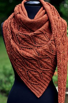 an orange knitted shawl sitting on top of a mannequin