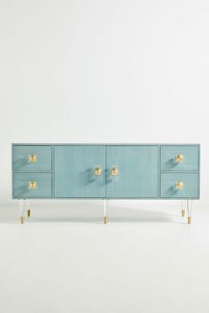 a blue cabinet with gold handles and drawers on it's sides, against a white background