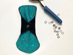 the scissors are next to some fabric and beads on a white table with a blue comb