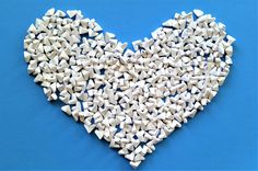 a heart shape made out of small white objects on a blue background with space for text