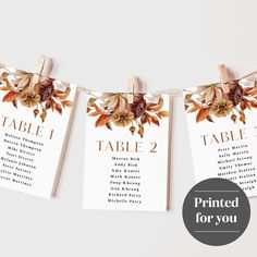 wedding seating cards hanging from clothesline with flowers and leaves on them, printed for you