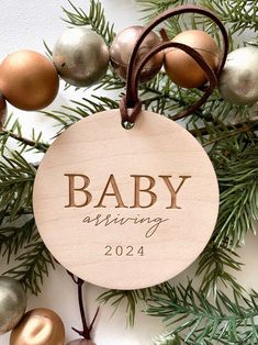 a baby's first christmas ornament hanging from a tree with ornaments around it