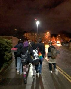 several people walking down the sidewalk at night