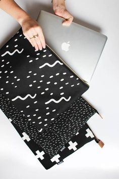 a woman is using her laptop on top of some cloths that are stacked together