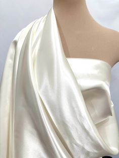 the back of a woman's white dress with an asymmetric draped over it