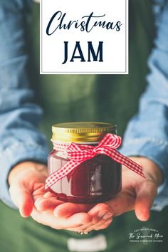 a person holding a jar with jam in it and the words christmas jam on top