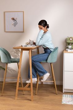 a woman sitting at a table with a cup of tea in front of her,