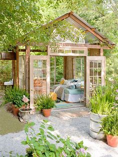 a garden shed with lots of potted plants in the front and side yard area