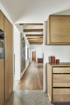 a long hallway with wooden cabinets and drawers on both sides, leading to the kitchen