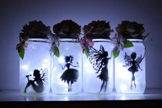 three mason jars with fairy silhouettes and flowers in them are lit up at night