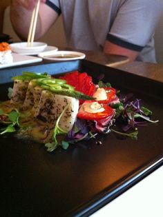 a man sitting at a table in front of a plate of food with vegetables on it