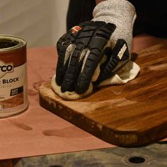 a pair of gloves on top of a wooden table next to a can of paint