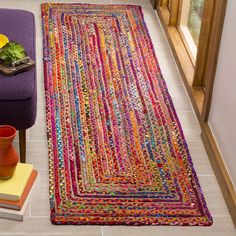 a living room with a purple couch and colorful rug