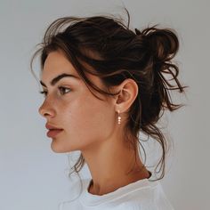 a woman with her hair in a bun and wearing gold hoop earrings on top of her head