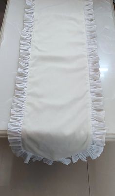 a bed with white sheets and ruffles on it